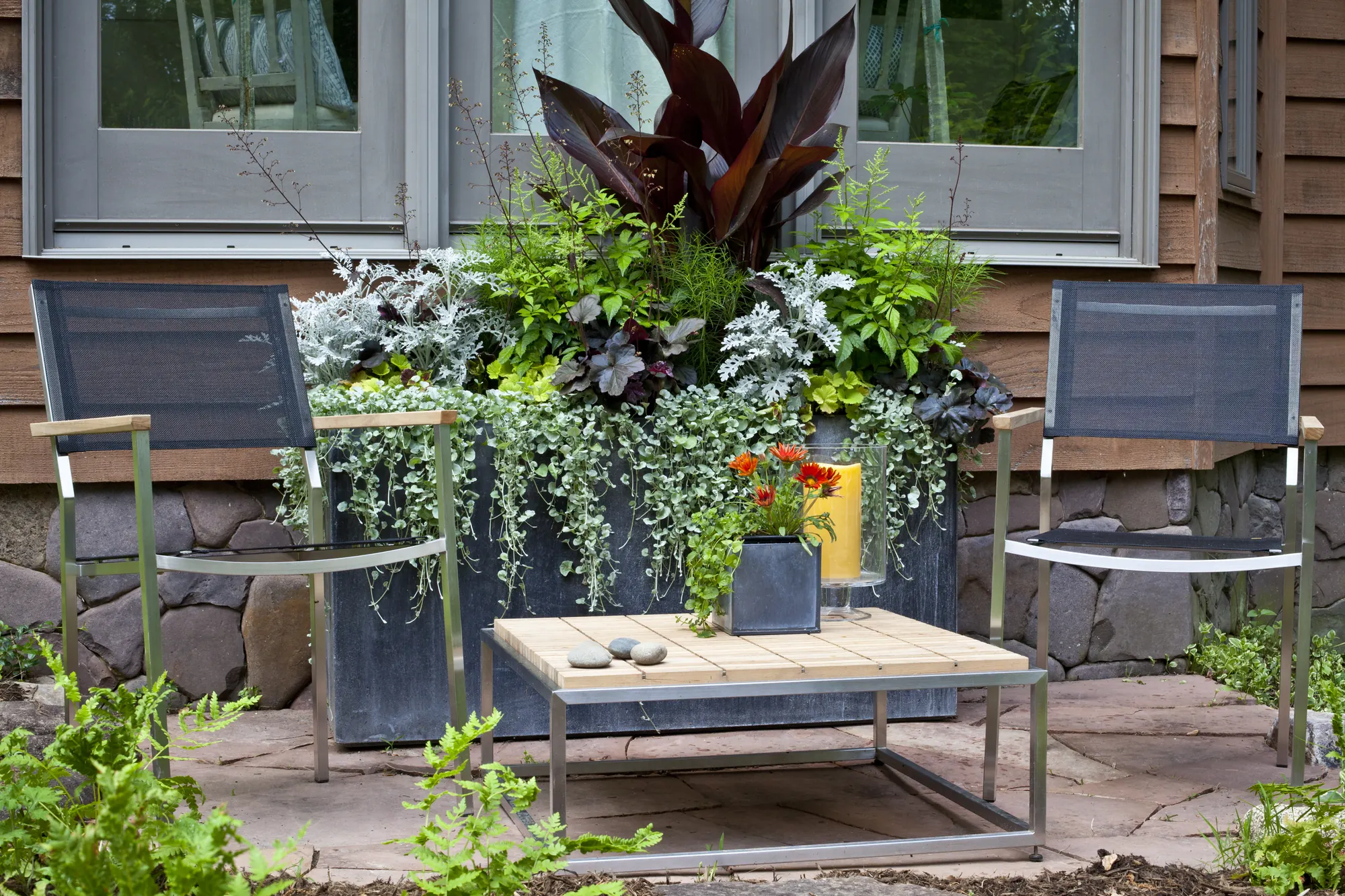 A Plantology potscape planter with lounge chairs on a flagstone patio