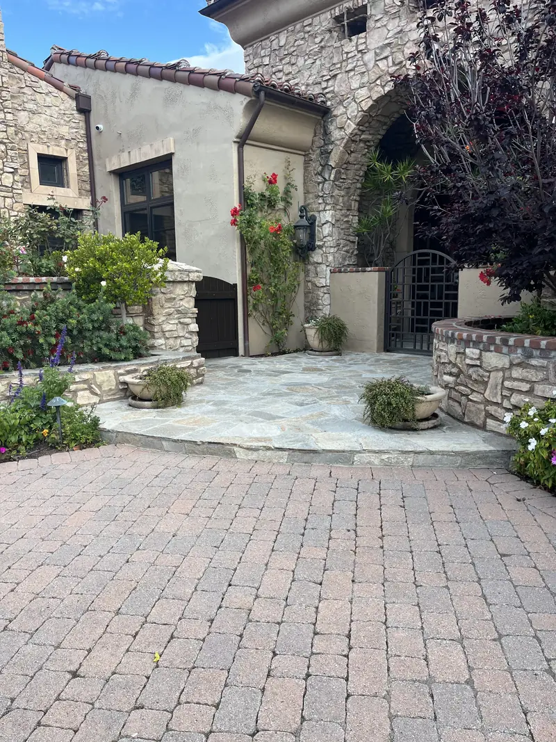 A stone entry court with flagstone and planted beds