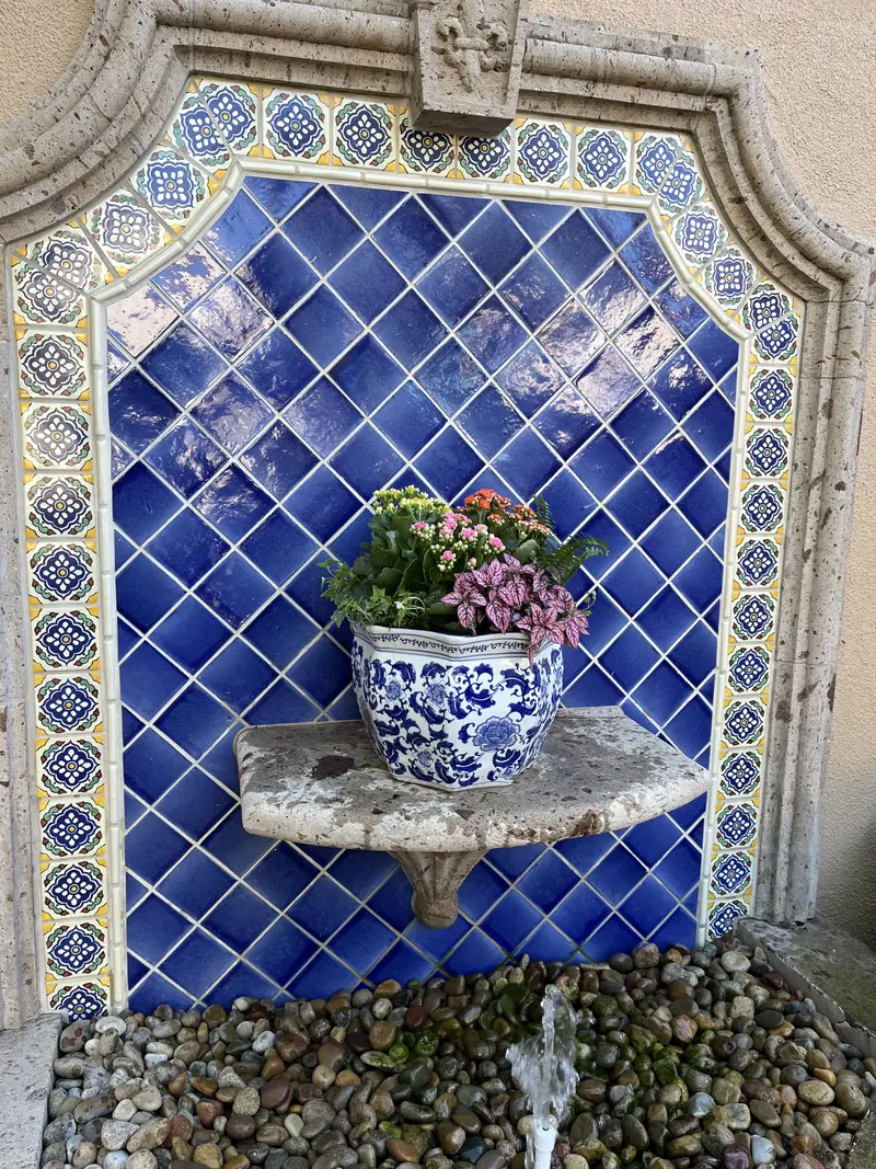 A blue and white pot set into a tiled wall fountain
