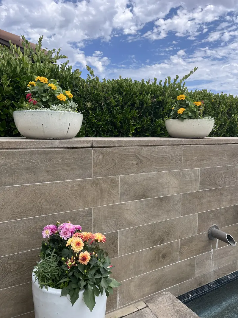 White bowls of flowers along a water wall