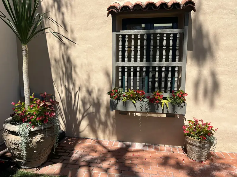 Red begonias in a window box and two planted urns